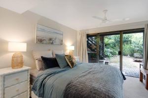 a bedroom with a bed and a sliding glass door at Kookaburra Beach House - 3 bedroom home in Tura Beach