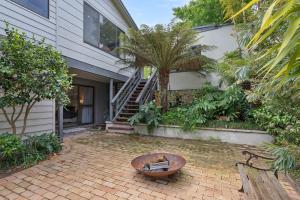 a house with a brick patio with a table in front of it at Kookaburra Beach House - 3 bedroom home in Tura Beach