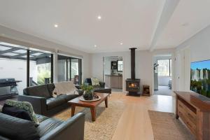 a living room with a couch and a fireplace at Kookaburra Beach House - 3 bedroom home in Tura Beach