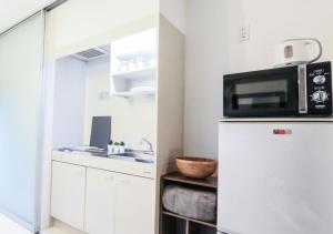 a kitchen with a microwave on top of a refrigerator at NEW Heart of Shibuya Prime Studio, Kamiyama Inn! in Tokyo