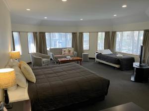 a bedroom with a bed and a living room with a couch at Fitzherbert Castle Motel in Palmerston North