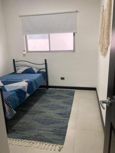 a bedroom with a bed with a window and a rug at Hermoso Apartamento en Alajuela in Alajuela