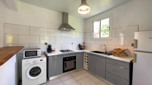 eine Küche mit einem Herd, einer Waschmaschine und einem Trockner in der Unterkunft Casa Tropical · T3 Calme & Spacieux in Le Lamentin