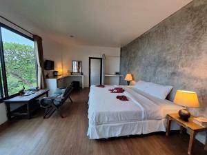 Schlafzimmer mit einem großen weißen Bett, einem Schreibtisch und einem Fenster in der Unterkunft Seabreeze @ Koh Mak in Ko Mak