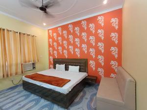 a bedroom with a bed with an orange wall at Hotel O Home HR Homes in Ayodhya