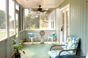 a screened porch with two chairs and two windows at Hadley's House - A Country 3 Bdrm with Screened-In Porch in New Braunfels