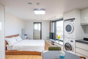 a bedroom with a bed and a washing machine at Haedam House in Jeju