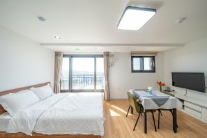 a white bedroom with a bed and a television at Haedam House in Jeju