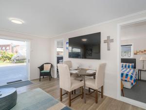 a dining room with a table and chairs and a cross on the wall at Beside the sea, park up and relax - Just 20 steps to the beach - Wi-Fi & Linen in Whitianga