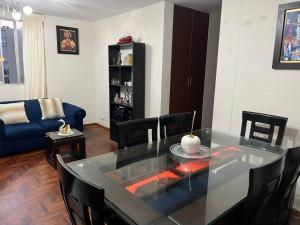 ein Wohnzimmer mit einem Glastisch und einem blauen Sofa in der Unterkunft Depa en san Miguel in Lima
