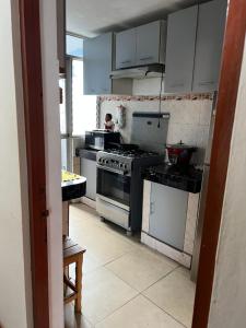 een keuken met witte kasten en een fornuis met oven bij Depa en san Miguel in Lima