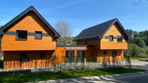 uma casa laranja com um telhado preto em Urlaub am Schwarzbach mit Sauna und Whilpool em Bütgenbach