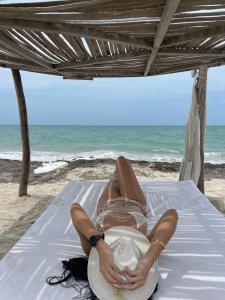 a woman laying on a bed on the beach at Aiwa Hotel in Mayapo