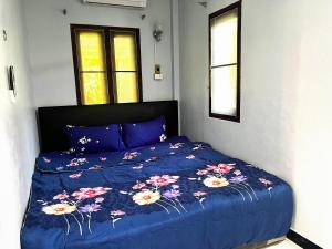 a bed with a blue comforter with flowers on it at 2BR Maryam villa near Tesco & beach. in Bang Tao Beach