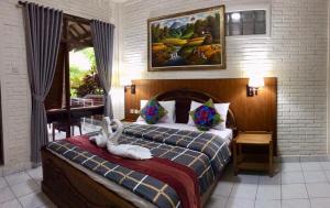a bedroom with a bed with two swans on it at Dewa Bharata Bungalows Ubud in Ubud