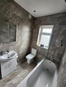 a bathroom with a tub and a sink and a toilet at Cosy Worsley Home with a Garden Bar! in Manchester