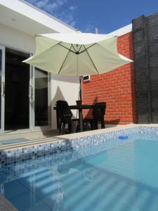 um pátio com uma mesa e um guarda-sol ao lado de uma piscina em Casa de Playa en Colan Casa Merino. em Paita