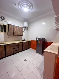 a kitchen with a refrigerator and a tile floor at رواح للشقق المخدومة السداد in Taif
