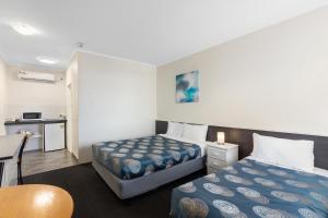 a hotel room with two beds and a table at Red Carpet Motel in Mount Gambier