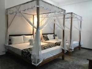 two beds in a room with two canopy beds at Peacock Riverside Eco Lodge in Udawalawe