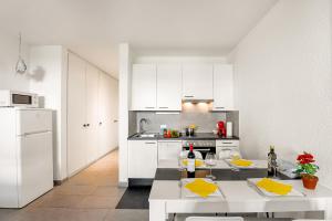 uma cozinha com armários brancos e uma mesa com copos de vinho em Holiday Home With Pool In Agno - Happy Rentals em Agno