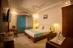1 dormitorio con 1 cama y ventilador de techo en Metro Plaza Hotel, en Mangalore