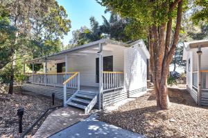 a white tiny house with a porch and stairs at NRMA Murramarang Beachfront Holiday Resort in Durras