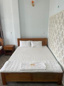 un letto in una camera con telaio in legno di KHÁCH SẠN HOÀNG QUANG a Biđong