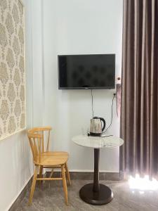 a table and a chair and a tv on a wall at KHÁCH SẠN HOÀNG QUANG in Biđong