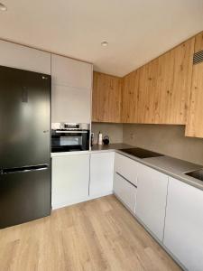 ヒホンにあるPiso de 2 habitaciones en centro, zona muy tranquila con playa a 2 min andandoの白いキャビネットと黒い冷蔵庫のあるキッチン