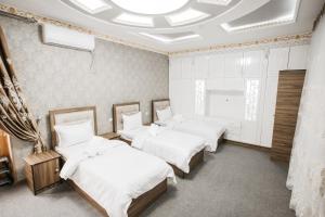 Zimmer mit 4 Betten und einer Decke in der Unterkunft Nazarxan Hotel in Samarkand