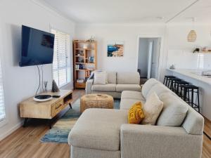 a living room with two couches and a flat screen tv at Surfmist House in Robe