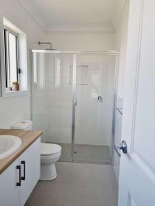 a white bathroom with a shower and a toilet at Surfmist House in Robe