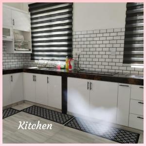 a kitchen with white cabinets and black and white tiles at Homestay Villa Muslim Kuala Terengganu with pool and parking in Kuala Terengganu