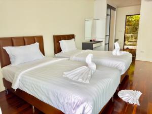 two beds in a room with white towels on them at Phi Phi Mountain Beach Resort SHA Certified in Phi Phi Islands