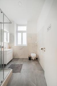 biała łazienka z toaletą i umywalką w obiekcie Chic Central City Rooms by Home2 w Wiedniu