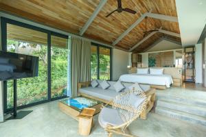 1 dormitorio con 1 cama, TV y sofá en Villa Escape Burasari, en Phuket