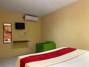 um quarto com uma cama e uma cadeira verde em RedDoorz near Gedung Kesenian Palopo em Palopo