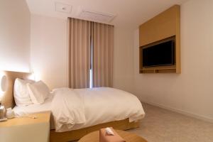 a hotel room with a bed and a flat screen tv at Goyang Hotel Yuji in Goyang
