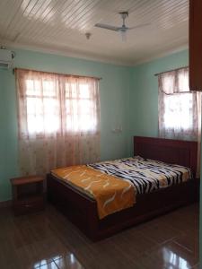 a bedroom with a bed in a room with two windows at Résidence Agnès et Victor (RAV) in Bangui