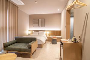Habitación de hotel con cama y silla en Goyang Hotel Yuji en Goyang