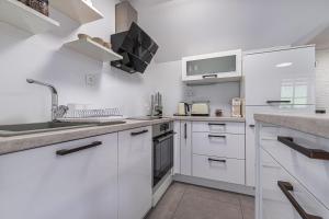 a white kitchen with white cabinets and a sink at Vineyard Cottage Radovlja With Sauna - Happy Rentals in Smarjeske Toplice