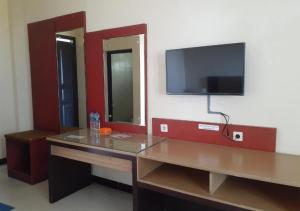 a room with a desk and a tv on a wall at Hotel Agung Putra in Banyumas