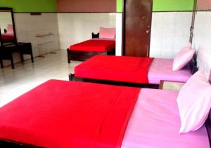 a room with three beds with red sheets at Hotel Agung Putra in Banyumas
