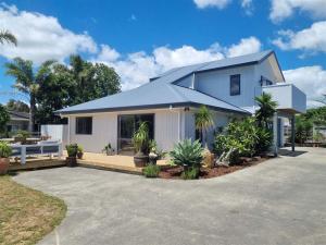 a white house with a blue roof at Great for Couples - Families - Groups in Mangawhai