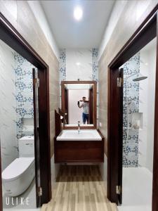 un homme prenant une photo d'une salle de bains avec lavabo dans l'établissement Namkhan Riverview Aphay, à Luang Prabang