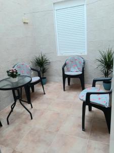 d'une terrasse avec 3 chaises, une table et une fenêtre. dans l'établissement Casa planta baja, à Elche