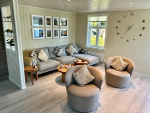 ein Wohnzimmer mit Sofas, Tischen und Fenstern in der Unterkunft Hardangerfjord View - luxury fjord-side holiday home in Øystese