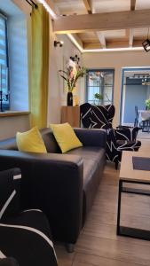 a living room with a black couch and yellow pillows at Haus Julia in Hintersee