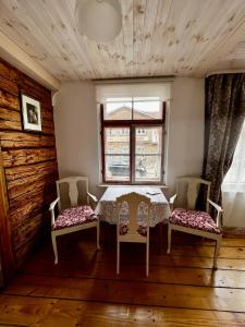 ein Esszimmer mit einem Tisch, 2 Stühlen und einem Fenster in der Unterkunft Juveliera apartamenti in Kuldīga